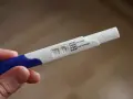 Test ciążowy w dłoni, widoczne dwa paski kontrolne. Wynik: brak okresu, test negatywny.