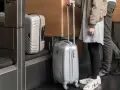 Osoby z bagażem Austrian Airlines czekają przy stanowisku odprawy.