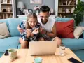 Szczęśliwa para z testem ciążowym na ekranie laptopa. Czy da się zaplanować płeć dziecka? Ich radość sugeruje, że odkryli coś ekscytującego.