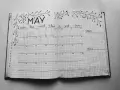 Otwarty notatnik z kalendarzem na maj, ozdobiony gałązkami. Idealny do planowania i nauki, jak prowadzić bullet journal.