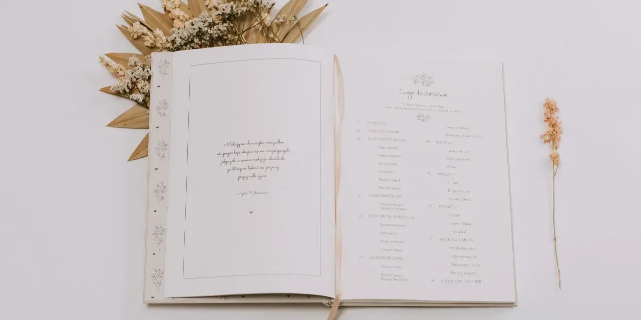 Otwarta księga z motywami roślinnymi, idealna na pierwszy album dziecka. Zawiera spis treści z rozdziałami takimi jak "Metryczka", "Roczniak" i "Dwulatek".