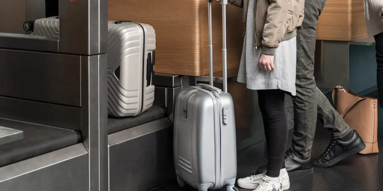 Osoby z bagażem Austrian Airlines czekają przy stanowisku odprawy.