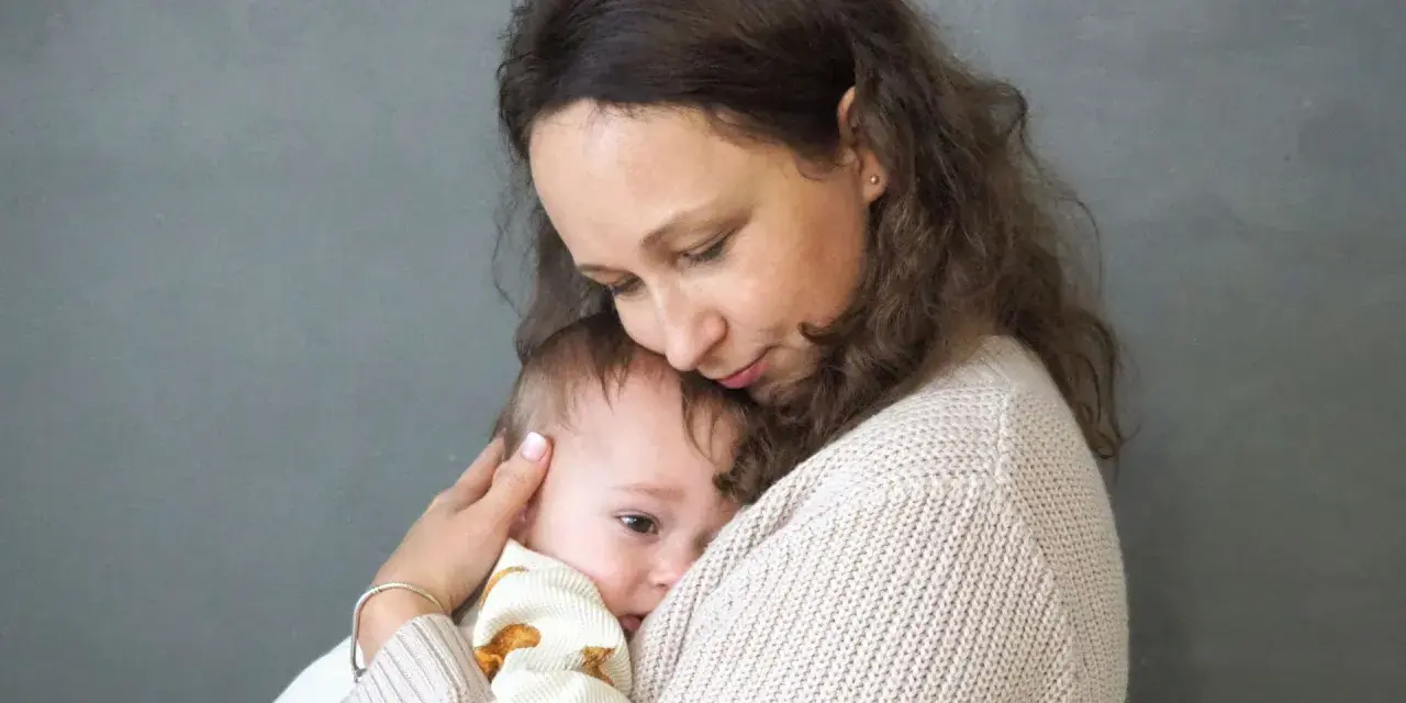 Matka tuli dziecko, które przeżywa lęk separacyjny. Jej delikatny dotyk i bliskość uspokajają malucha.