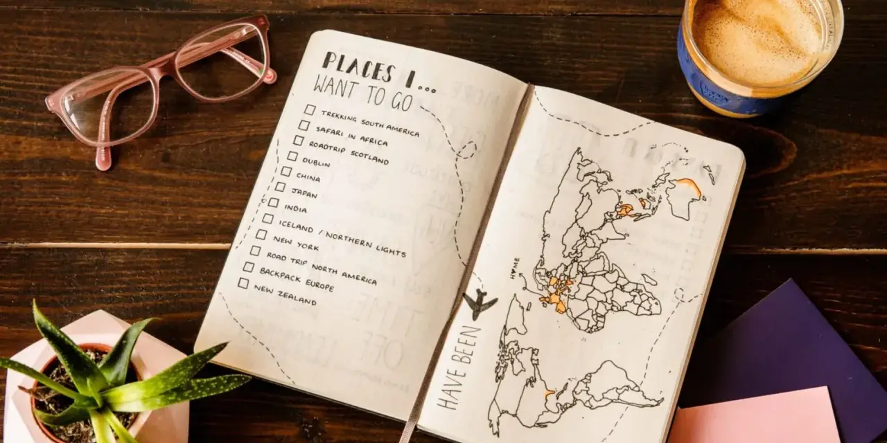 Otwarty planer podróży z listą miejsc do odwiedzenia i mapą świata. Kawa i okulary dopełniają inspirującą scenę.
