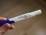 Test ciążowy w dłoni, widoczne dwa paski kontrolne. Wynik: brak okresu, test negatywny.