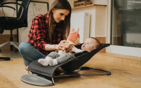 Mama bawi się z dzieckiem w bujaczku Babybjorn. Od kiedy maluch może z niego korzystać? Od pierwszych dni życia!