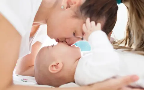 Ciepły pocałunek mamy dla jej 3 miesięcznego dziecka.