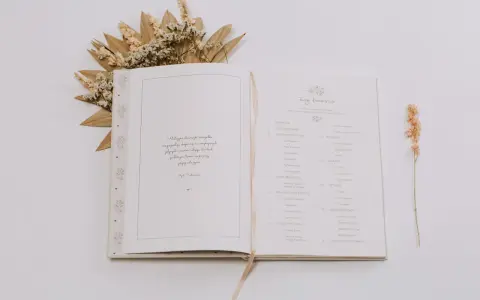Otwarta księga z motywami roślinnymi, idealna na pierwszy album dziecka. Zawiera spis treści z rozdziałami takimi jak "Metryczka", "Roczniak" i "Dwulatek".