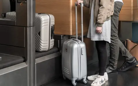 Osoby z bagażem Austrian Airlines czekają przy stanowisku odprawy.