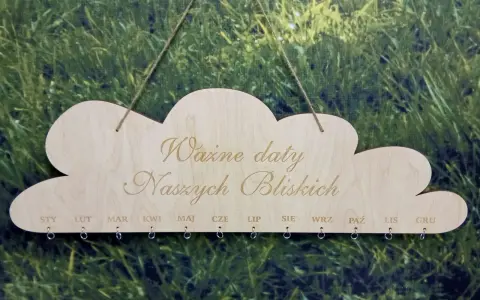 Drewniany kalendarz w kształcie chmurki z napisem "Ważne daty Naszych Bliskich". Poniżej miesiące od STY do GRU, z kółeczkami do zawieszania pamiątek. Idealny do zaznaczania każdego dnia urodzenia.