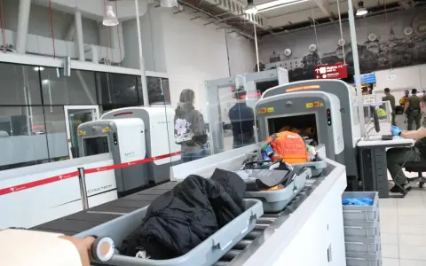 Kontrola paszportowa na lotnisku. Bagaże przechodzą przez skaner, a podróżni czekają na swoją kolej.