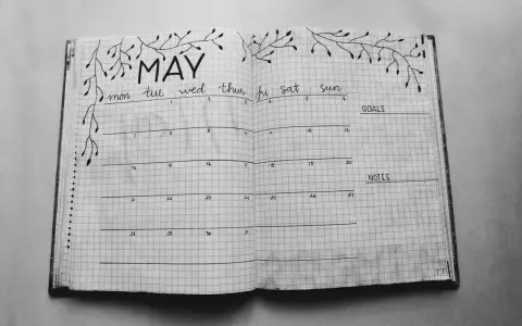 Otwarty notatnik z kalendarzem na maj, ozdobiony gałązkami. Idealny do planowania i nauki, jak prowadzić bullet journal.