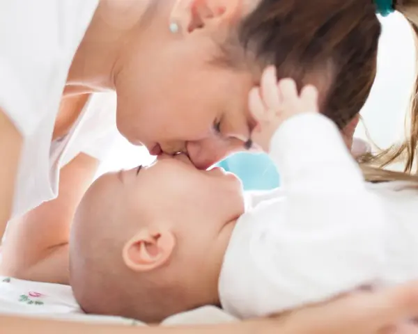 Ciepły pocałunek mamy dla jej 3 miesięcznego dziecka.