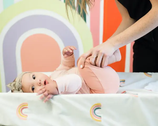 Niemowlę ćwiczy obręcz barkową. Mama delikatnie podnosi nóżki dziecka, wspierając jego rozwój.