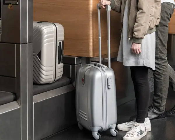 Osoby z bagażem Austrian Airlines czekają przy stanowisku odprawy.