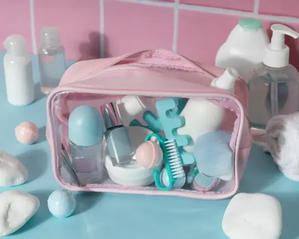 Różowa kosmetyczka z akcesoriami do makijażu i pielęgnacji, w tym perfumy w bagażu podręcznym.