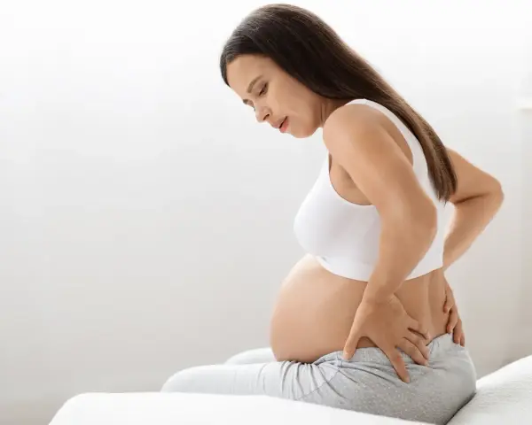 Kobieta w 38 tygodniu ciąży z bólem pleców, trzymająca się za lędźwie.