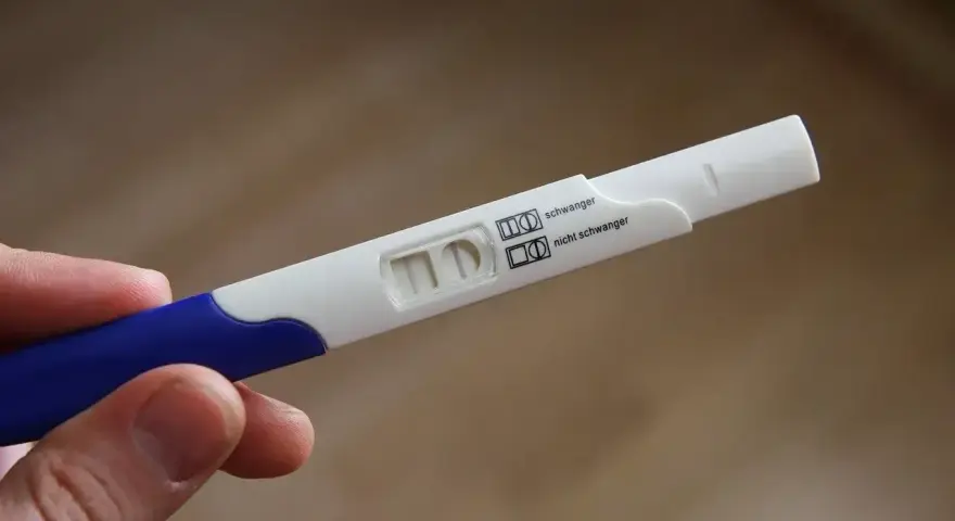 Test ciążowy w dłoni, widoczne dwa paski kontrolne. Wynik: brak okresu, test negatywny.