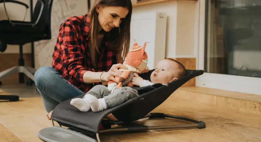 Mama bawi się z dzieckiem w bujaczku Babybjorn. Od kiedy maluch może z niego korzystać? Od pierwszych dni życia!