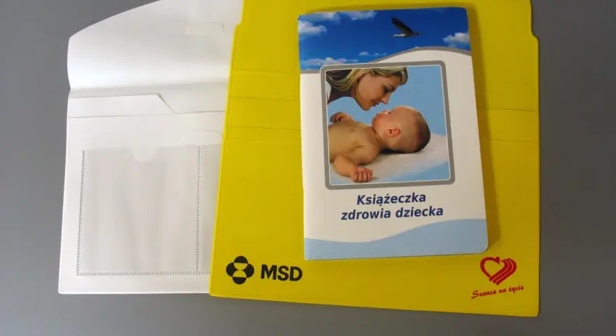 Żółta teczka na dokumenty dziecka z książeczką zdrowia.