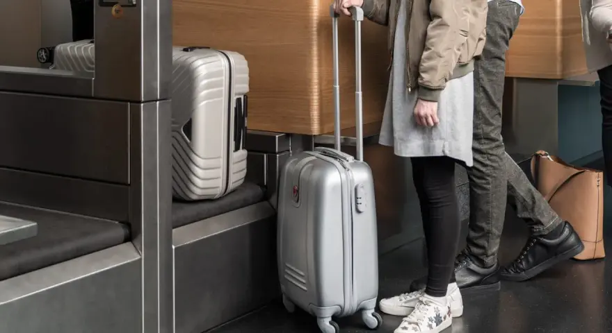 Osoby z bagażem Austrian Airlines czekają przy stanowisku odprawy.