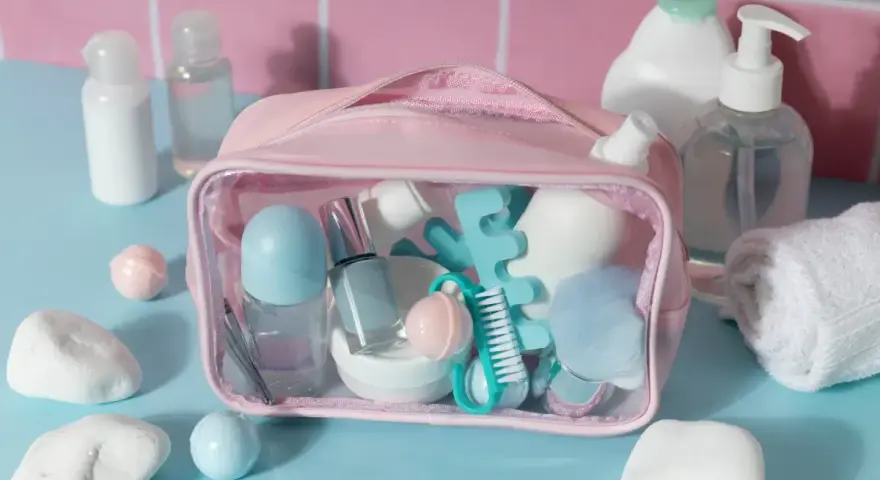 Różowa kosmetyczka z akcesoriami do makijażu i pielęgnacji, w tym perfumy w bagażu podręcznym.