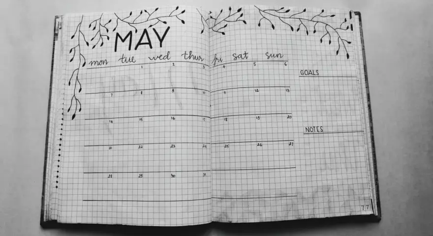 Otwarty notatnik z kalendarzem na maj, ozdobiony gałązkami. Idealny do planowania i nauki, jak prowadzić bullet journal.