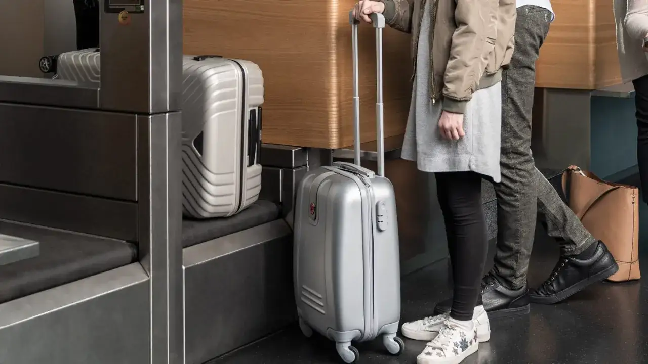 Osoby z bagażem Austrian Airlines czekają na odprawę. Srebrne walizki gotowe do podr&oacute;ży.