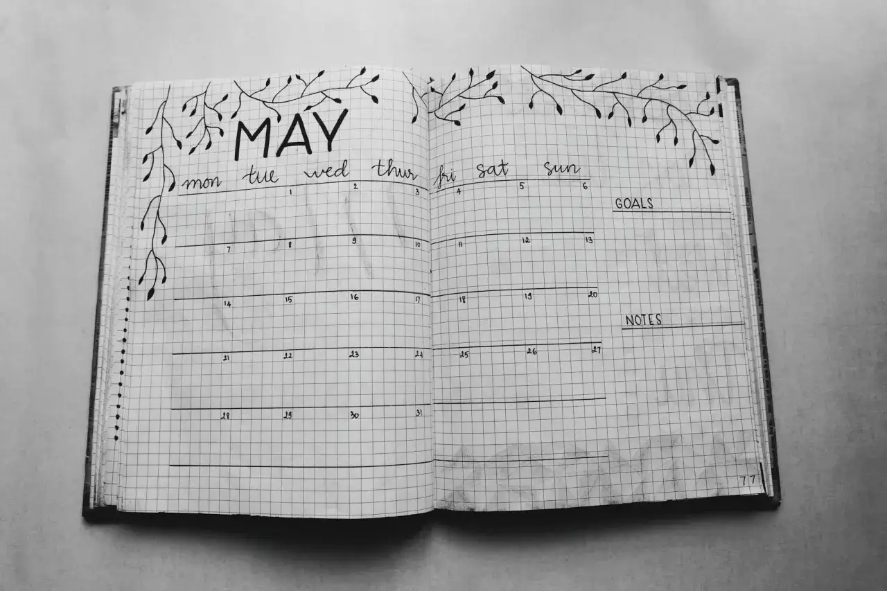 Piękne bullet journal pomysły na strony: kalendarz na maj z ozdobnymi gałązkami, sekcje na cele i notatki.