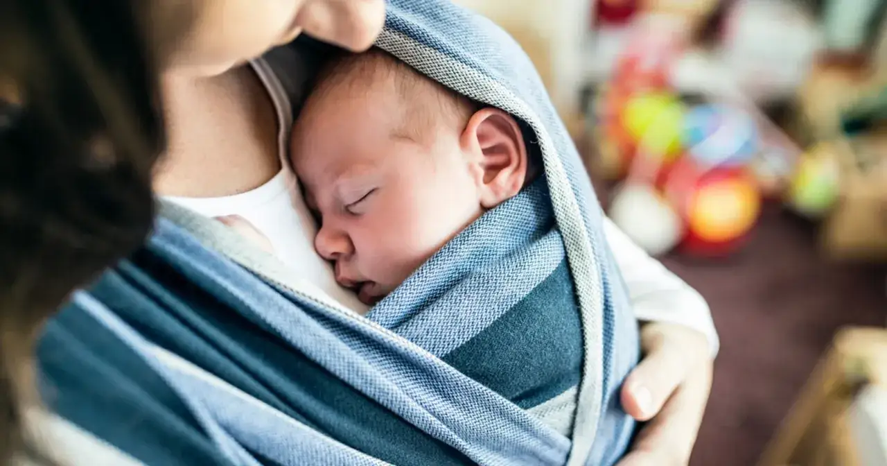 Malutkie dziecko śpi wtulone w rodzica, otulone chustą. Nawet high need baby kiedy mija, czuje się bezpiecznie.
