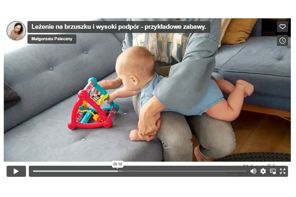 Niemowlę na brzuszku, ćwiczące wysoki podp&oacute;r, bawi się kolorową zabawką.